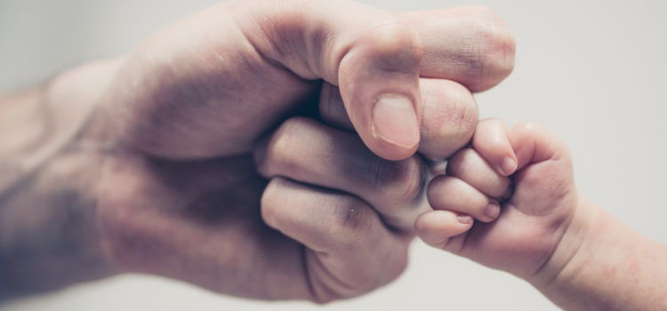 Fist of Dad and Newborn Baby